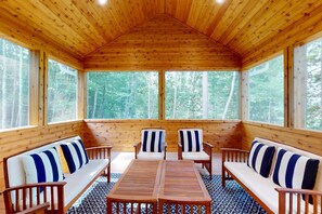 A cabin with a wooden interior, a central table, and four chairs with striped cushions.