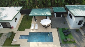 A rooftop pool area with lounge chairs, a table, and umbrellas. - Beautiful 3-bedroom house with AC in charming Puntarenas Province (Uvita)