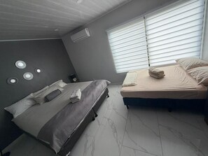 A bedroom with two beds, a ceiling fan, and a window with blinds. - Beautiful 3-bedroom house with AC in charming Puntarenas Province (Uvita)