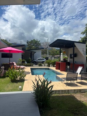 A backyard with a swimming pool, outdoor seating, and a covered patio area. - Beautiful 3-bedroom house with AC in charming Puntarenas Province (Uvita)