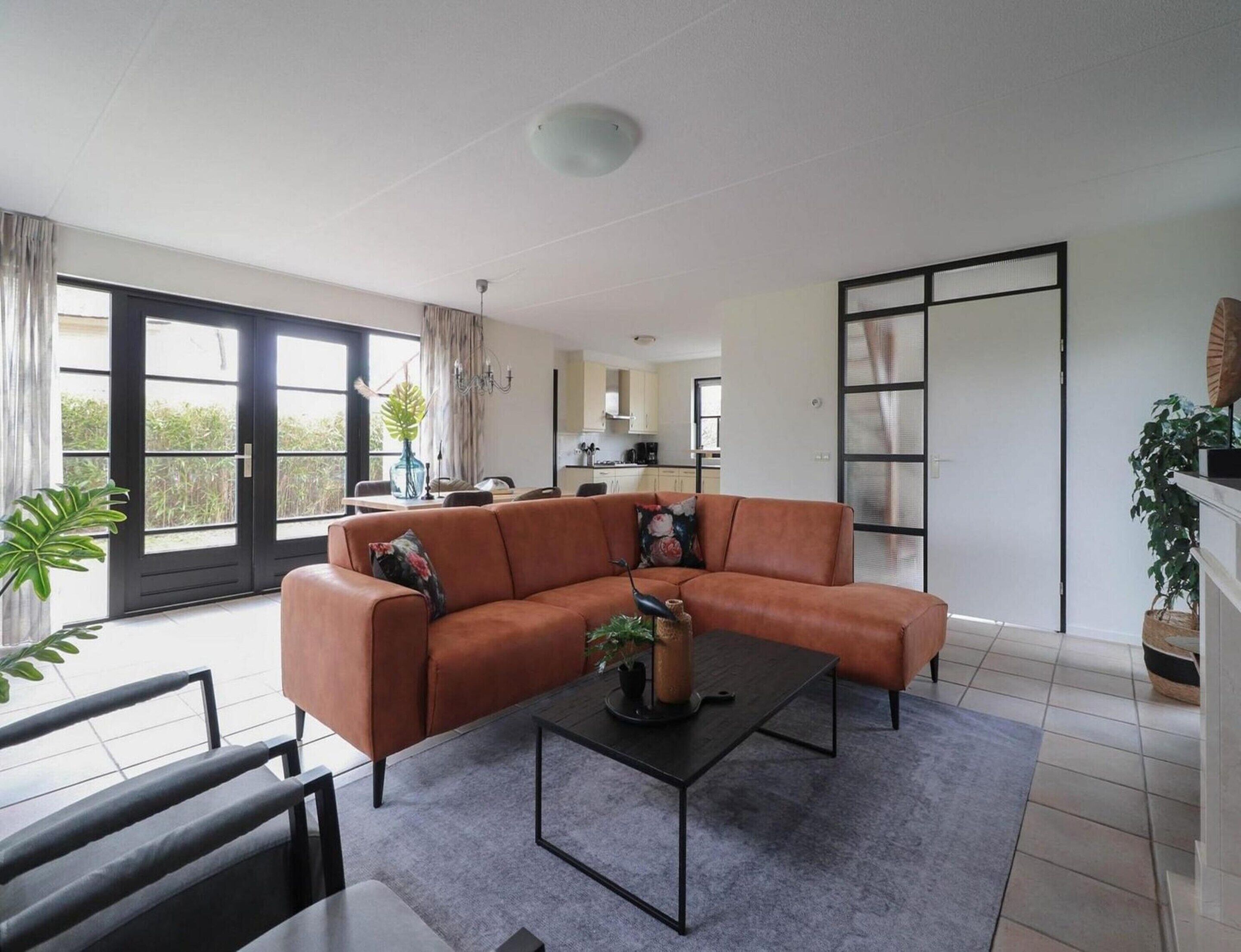 A modern living room with a sectional sofa, a coffee table, and a view of the kitchen through an open door.