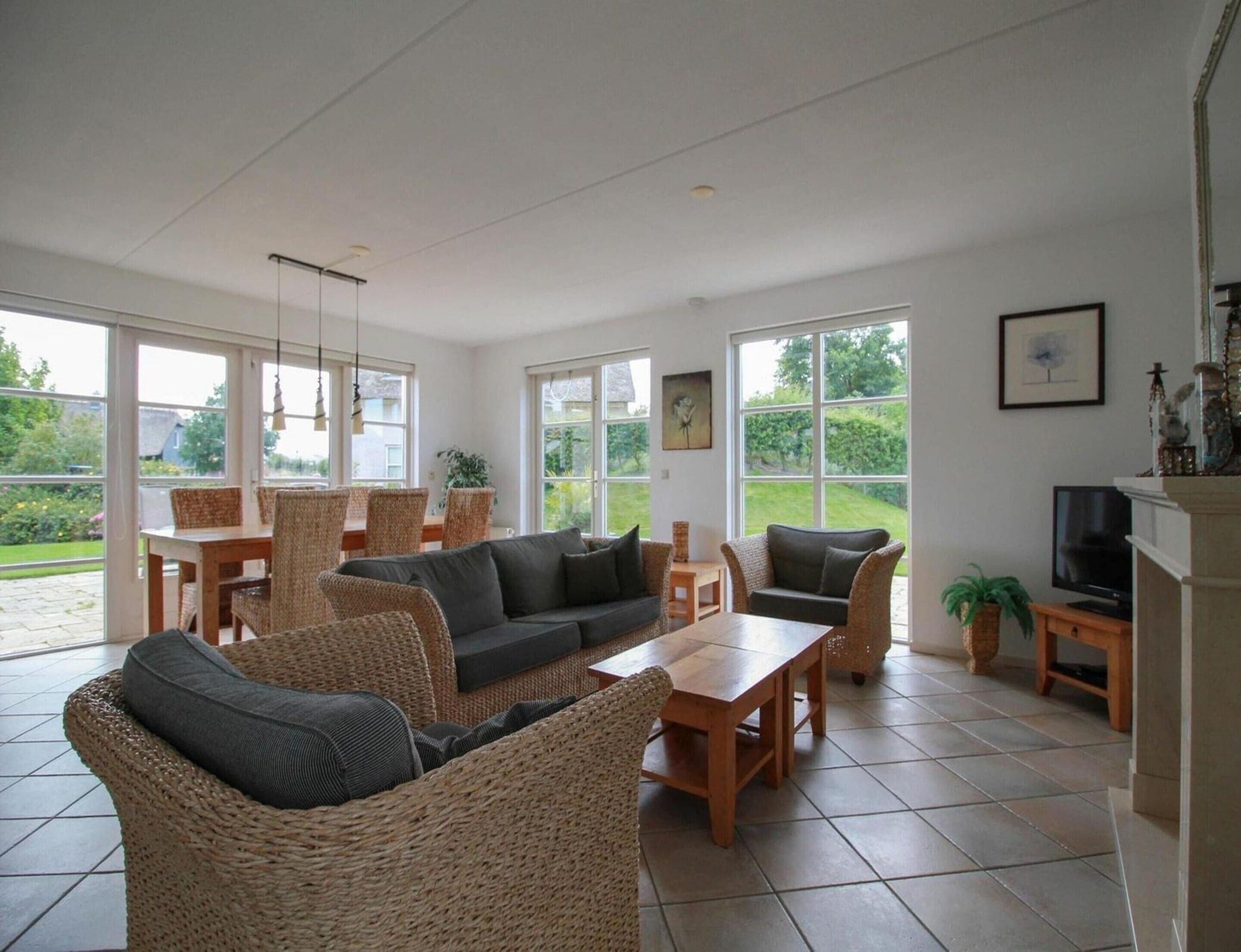 A spacious living area with a sofa, chairs, a table, and a television.