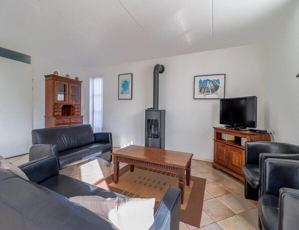 A living room with a sofa, a coffee table, a television, and a fireplace. - Attractive Dune Villa With Sauna (Makkum)