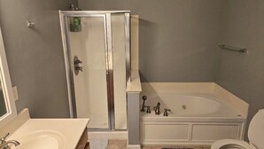 A bathroom with a glass shower enclosure, a bathtub, a toilet, and a sink. - CORP HOUSING:::
Spacious 5-bedroom house in amazing Winston-Salem with AC (Winston-Salem)