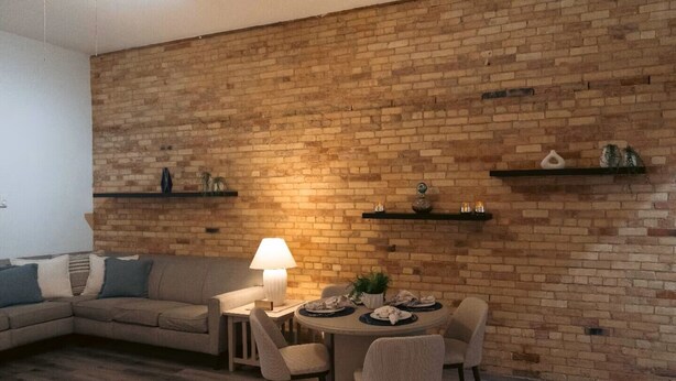 Una sala de estar con pared de ladrillo, una mesa redonda de comedor y un sofá.