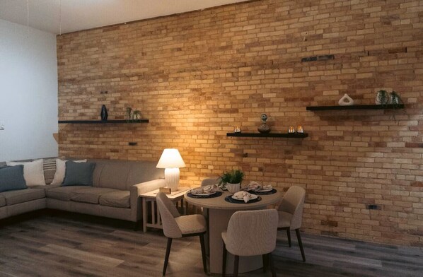 Una sala de estar con pared de ladrillo, una mesa redonda de comedor y un sofá.