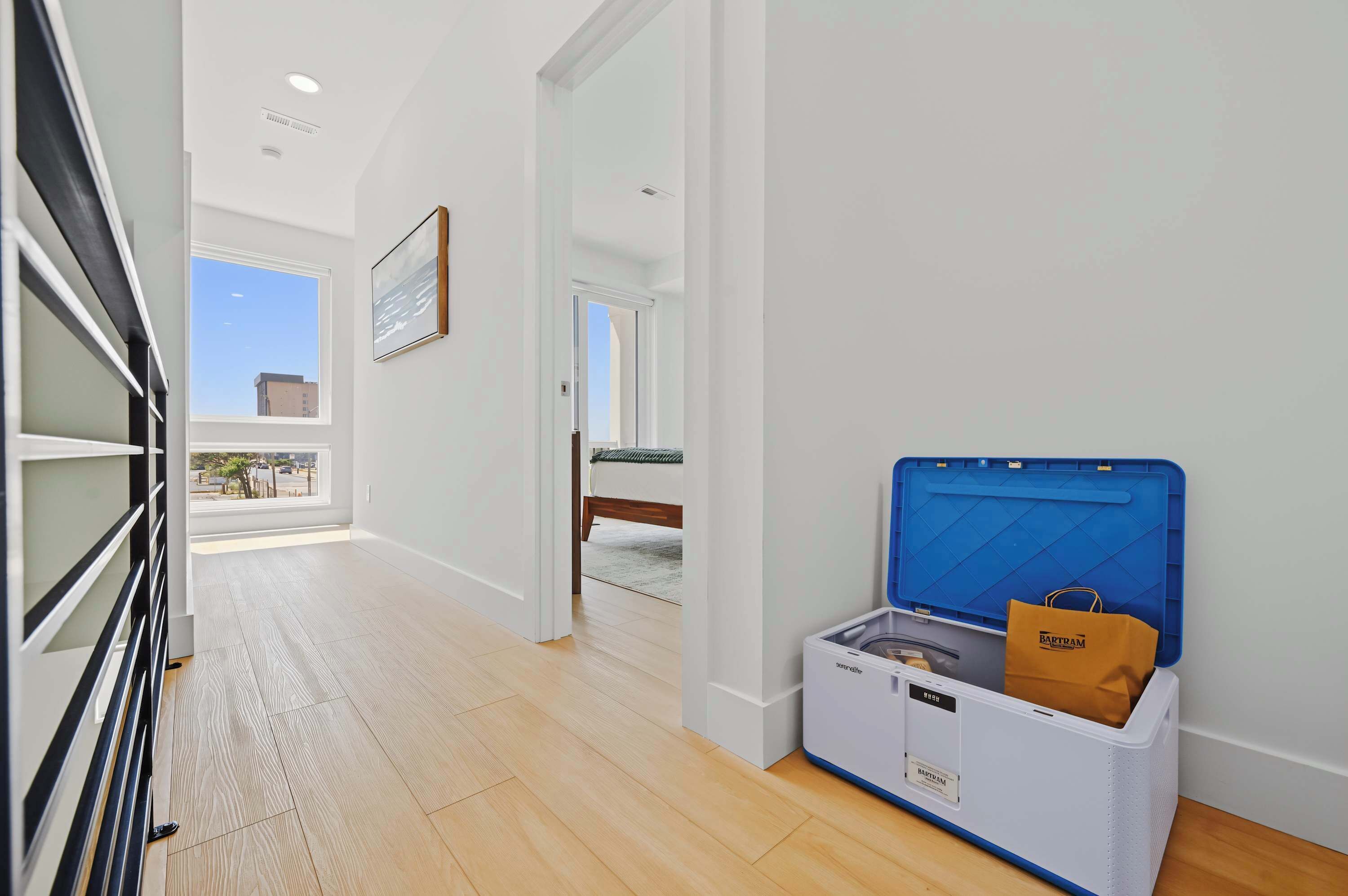 A hallway with a bed, a suitcase, and a blue storage unit.