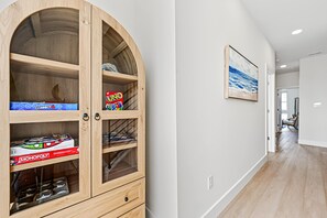 Ein Holzschrank mit Schubladen und Regalen, ein gerahmtes Bild an der Wand und ein Gang mit einer Tür am Ende.