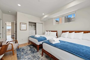 A hotel room with two beds, a desk, a chair, and a view of the cityscape. - The Coastal | Rooftop & Garage (Atlantic City)