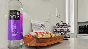 A bottle of Life WTR on a kitchen counter, a tray of chocolates, and a coffee machine. - Coastal Loop Retreat | Rooftop Deck + Garage (Atlantic City)