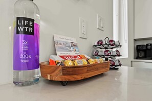 Eine Flasche Life WTR auf einer Küchenarbeitsplatte, eine Schokoladentafel und eine Kaffeemaschine.