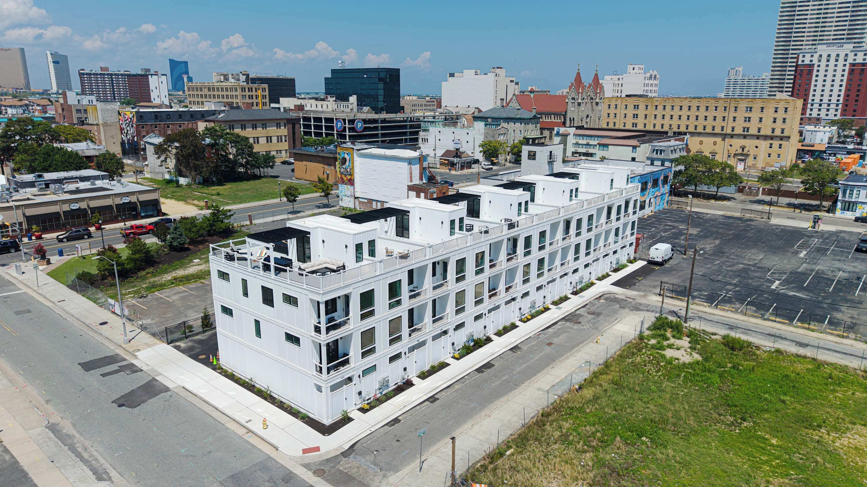 Ein mehrstöckiges Hotel mit modernem Design, gelegen in einem städtischen Gebiet mit Parkplatz und Stadtblick im Hintergrund.