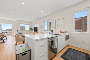 A modern apartment with a kitchen, dining area, and living space. - The Coastal | Rooftop & Garage (Atlantic City)