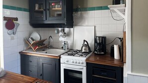 Una cocina con estufa, lavamanos, alacenas y una cafetera.