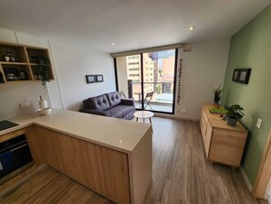 Un appartement moderne comprenant une cuisine, un coin repas et un salon avec un canapé et une table.
