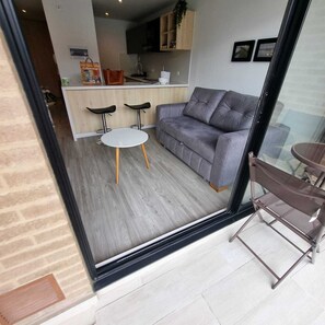 Un espace de vie moderne avec un canapé gris, une table ronde blanche et deux chaises noires.