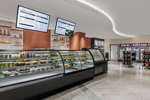 Eine Verkaufstheke mit verschiedenen Backwaren, einer Kaffeekarte und einer Speisekarte für Sandwiches in einem modernen Café.