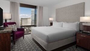 Une chambre d’hôtel avec un grand lit, deux tables de chevet, une chaise et un bureau.
