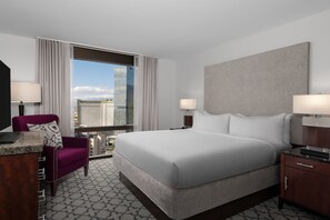 Ein Hotelzimmer mit einem großen Bett, zwei Nachttischen, einem Sessel und einem Schreibtisch.