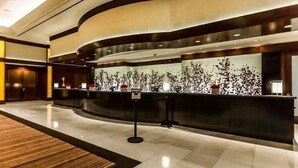 A modern hotel reception area with a curved reception desk, a large decorative wall, and a polished floor. - Free Valet Parking MGM Studio 1911 (Las Vegas)