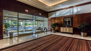Eine Hotelhalle mit Glastür, einer Rezeption und Topfpflanzen.