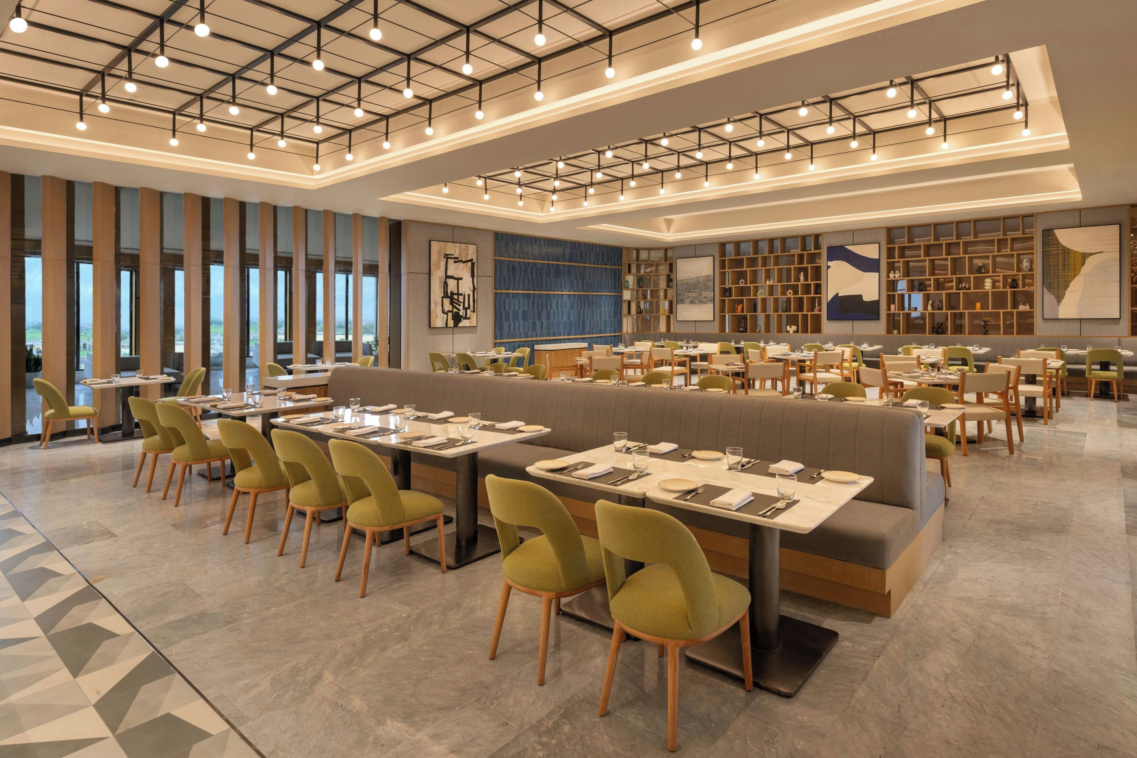 A modern restaurant with high ceilings, pendant lighting, and a variety of seating options including booths and tables.