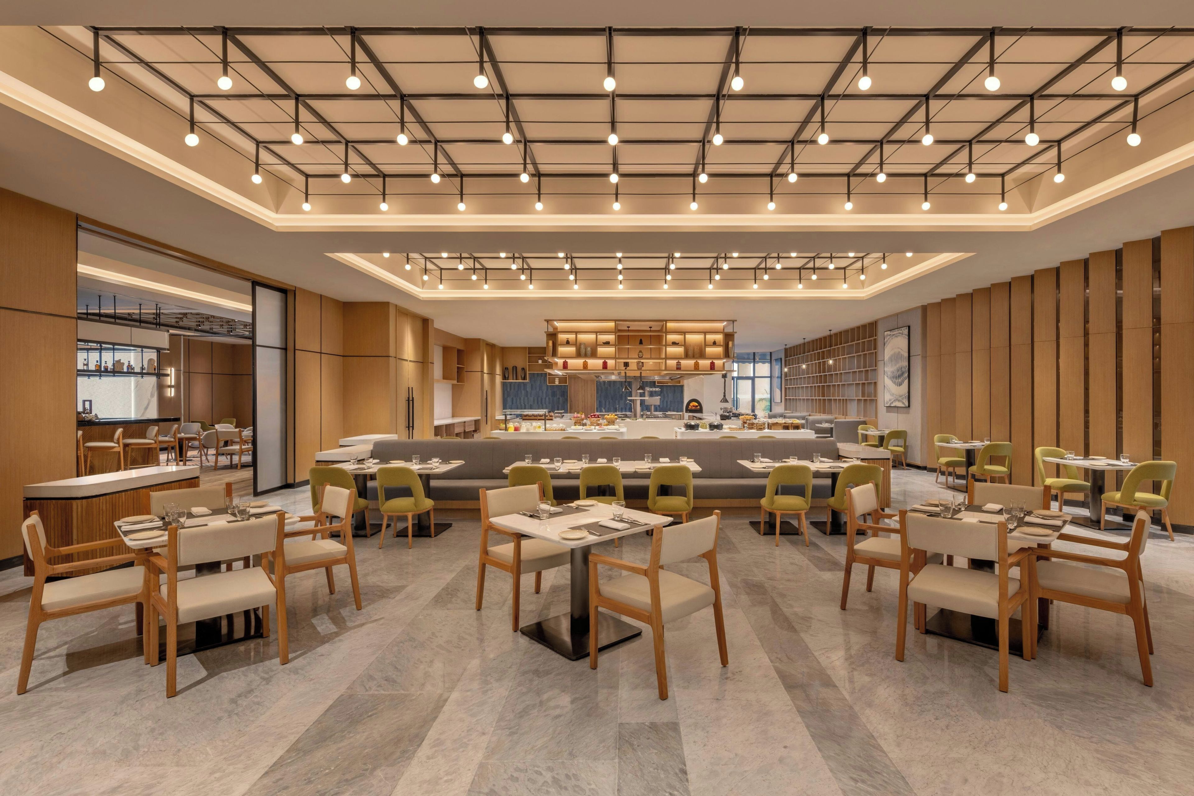 A modern restaurant with a central bar area, multiple dining tables, and booths.