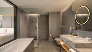 Un baño moderno con ducha envuelta en vidrio, una bañera grande y un tocador con espejo.