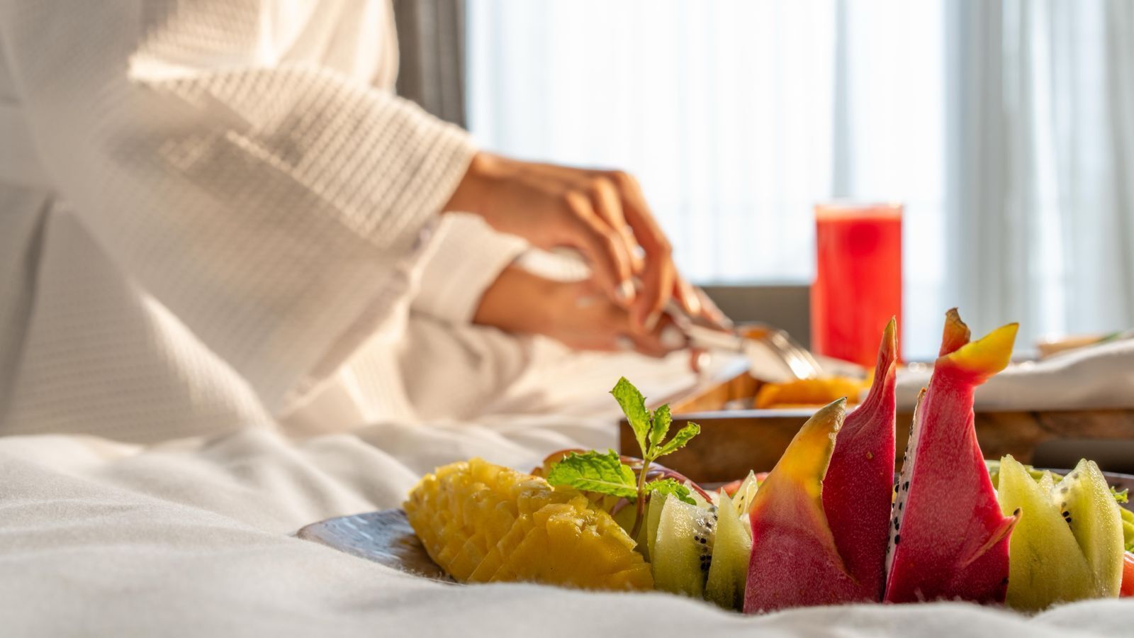 A breakfast setting with a plate of fruit and a red beverage.