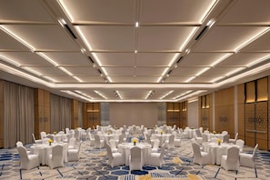 A large conference room with round tables, white chairs, and a patterned carpet.