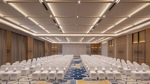A conference room with rows of white chairs, a patterned carpet, and a ceiling with recessed lighting. - Courtyard by Marriott Ghaziabad India (Ghaziabad)