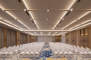 A conference room with rows of white chairs, a patterned carpet, and a ceiling with recessed lighting. - Courtyard by Marriott Ghaziabad India (Ghaziabad)