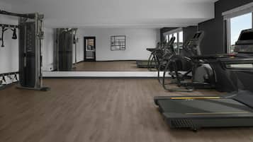 A gym with treadmills, a weight machine, and a mirror.