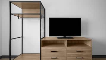 A room with a TV on a wooden cabinet, a metal shelving unit, and a white wall.