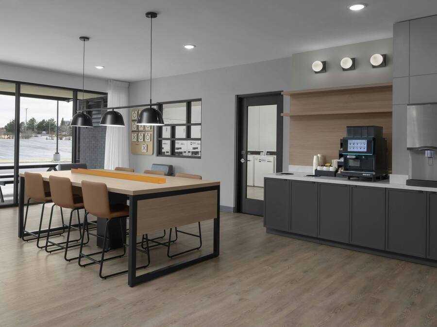 A modern kitchen with a dining area, a coffee machine, and a water dispenser.