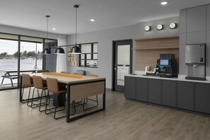 A modern kitchen with a dining area, a coffee machine, and a water dispenser. - StudioRes by Marriott Clearfield Layton (Clearfield)