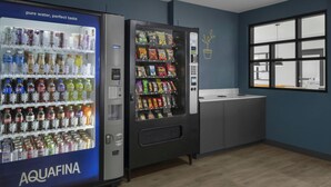 Zona de màquines expenedores amb un dispensador d'aigua etiquetat AQUAFINA i una màquina expenedora de llaminatures.