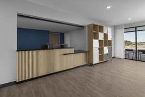 A modern reception desk with a blue accent wall, a wooden panel design, and a view of the city through large windows.