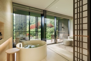 A modern bathroom with a large bathtub, a seating area with a table and chairs, and a view of a forest through floor-to-ceiling windows. - HOTEL THE MITSUI HAKONE, a Luxury Collection Hotel & Spa (Hakone)