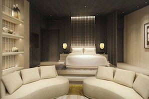Une chambre moderne avec un grand lit, deux canapés, une table de chevet et une étagère ornée d’objets décoratifs.