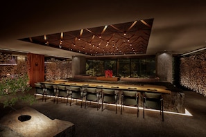 A modern bar area with a long counter and multiple chairs, a unique ceiling design, and a view of greenery outside. - HOTEL THE MITSUI HAKONE, a Luxury Collection Hotel & Spa (Hakone)