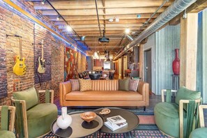 Ein gemütlicher Lounge-Bereich mit Ziegelwand, einer Couch und grünen Sesseln.
