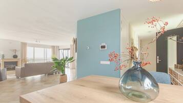 A modern living room with a wooden table, a blue accent wall, and a fireplace.
