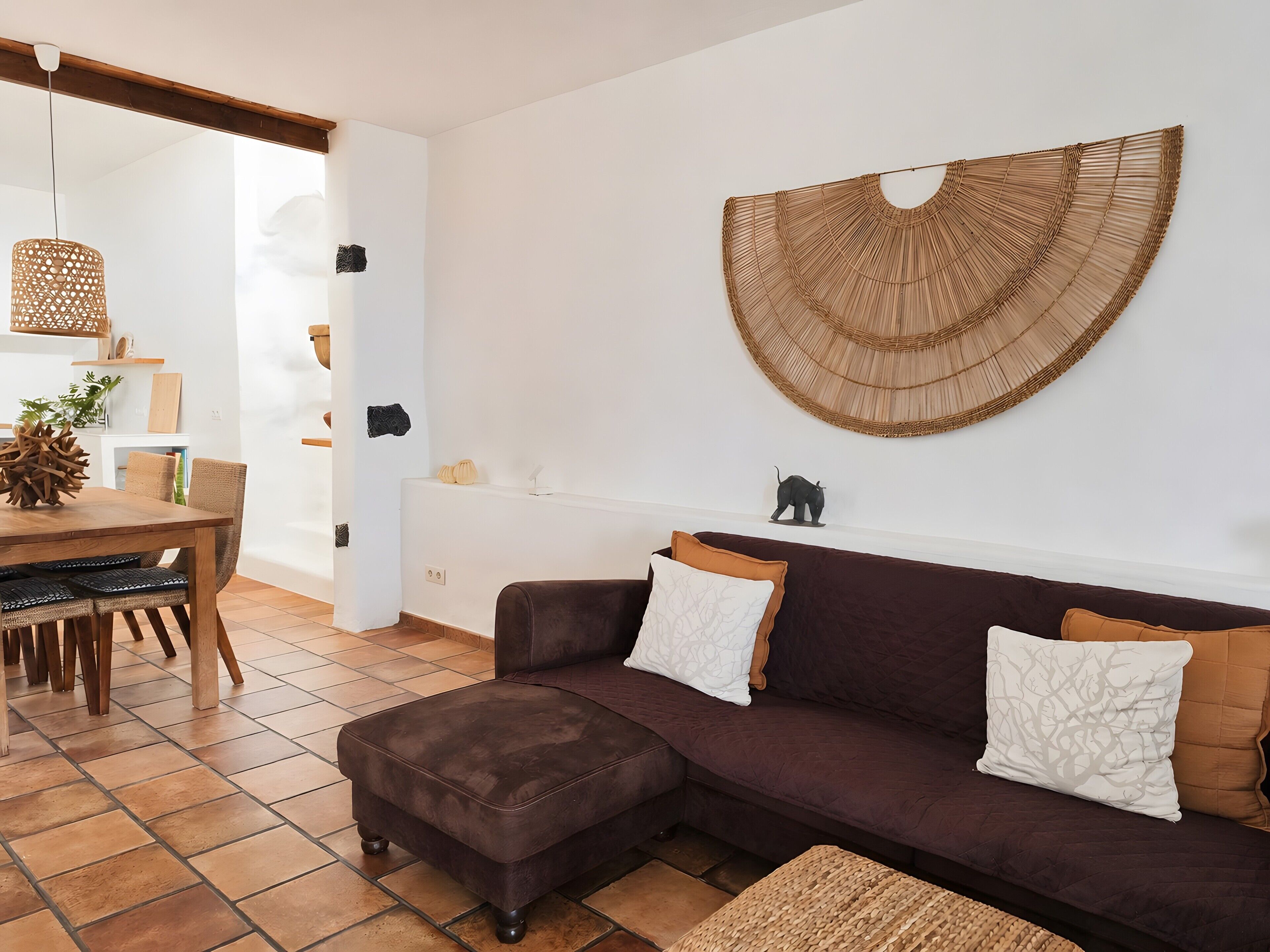 Un salon moderne avec un canapé marron, une table à manger et une grande décoration murale tissée.