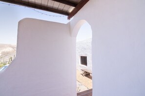 A white-walled room with a window and a view of a desert landscape.