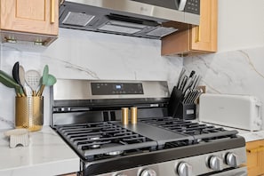 A kitchen with a stainless steel stove, a toaster, and wooden cabinets. - The Gaslamp Oasis (San Diego)