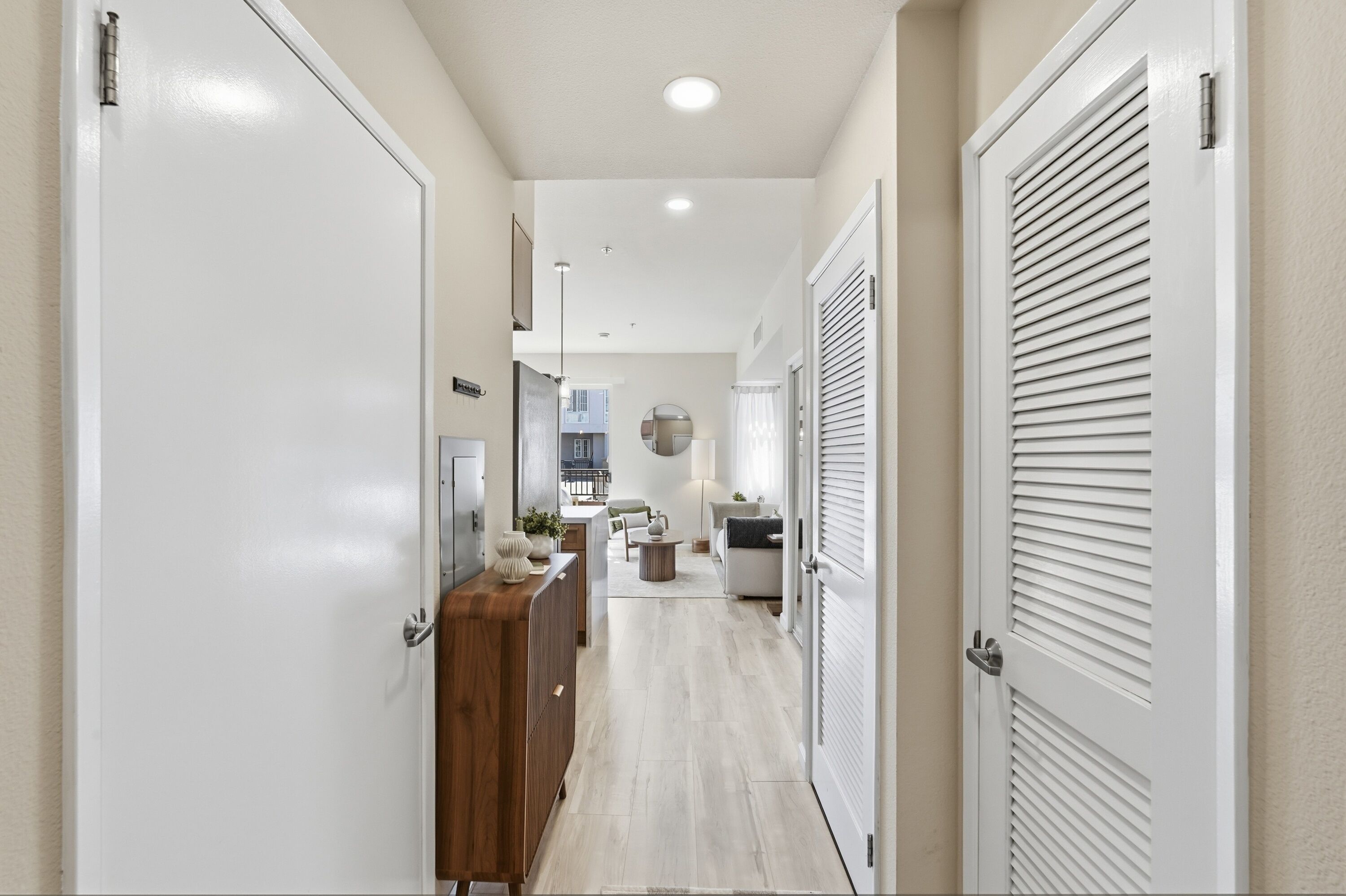 A hallway with a wooden cabinet, a white door, and a ceiling light.