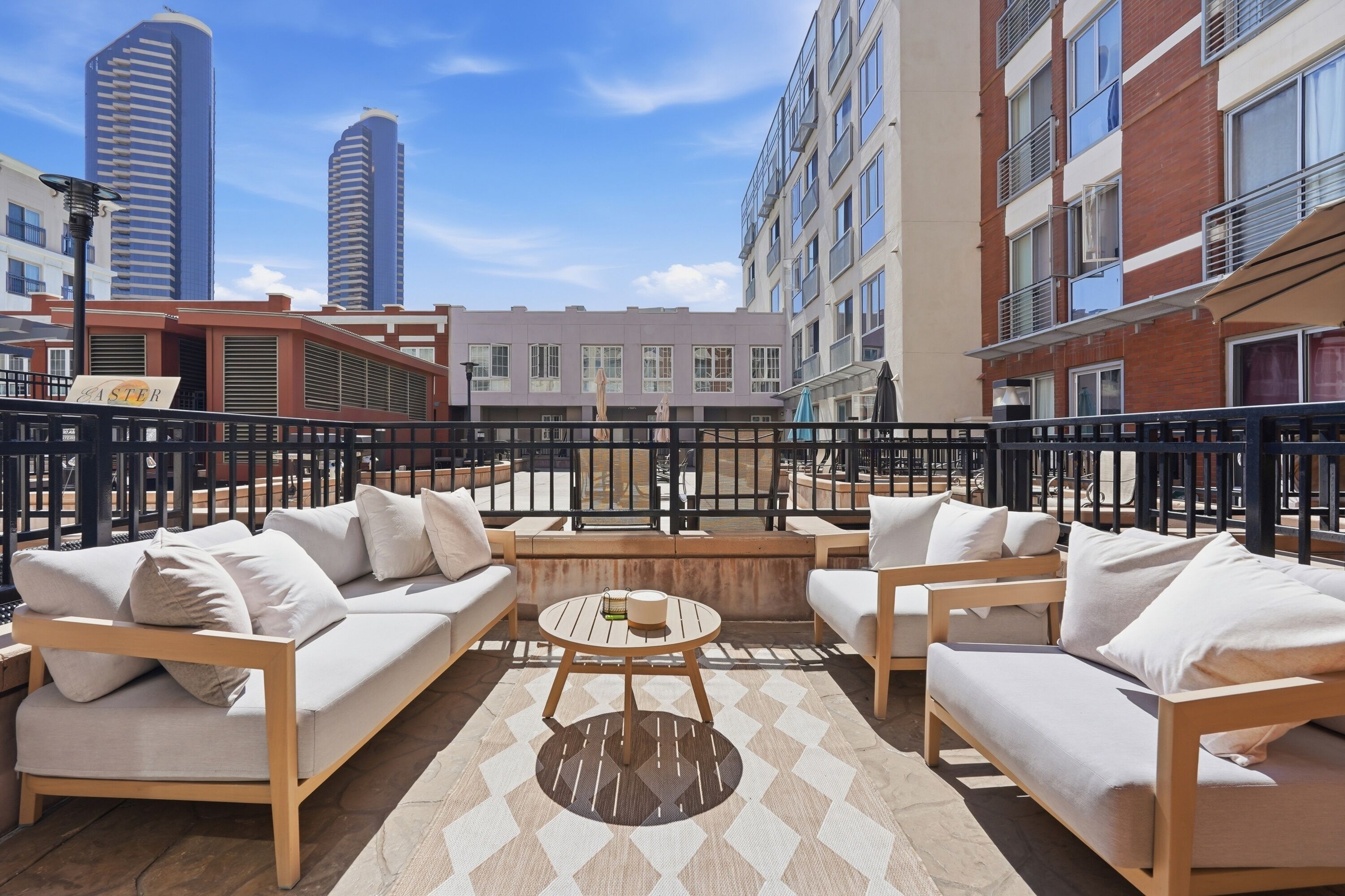 A rooftop terrace with outdoor seating, a view of surrounding buildings, and a sign reading 'EASTER'.