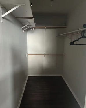 Un pasillo estrecho con suelo oscuro, paredes blancas y techo con vigas a la vista.