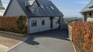 A two-story house with a sloped roof, a driveway, and a view of the sea. - Luxury Whitby Townhouse for 10 (Dyffryn Ardudwy)